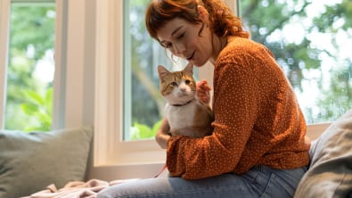 Mulher de suéter laranja segurando um gato